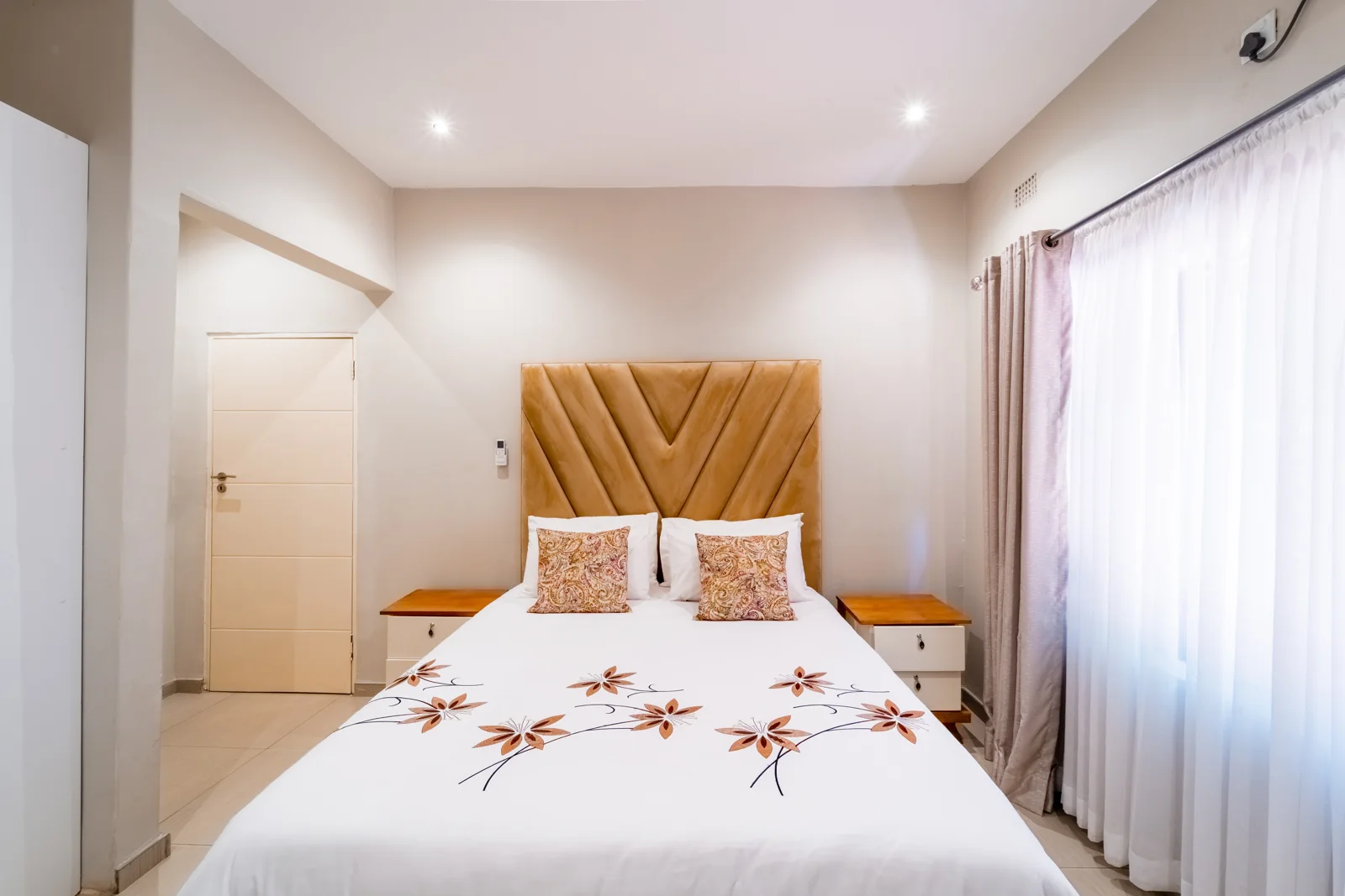 Double Bedroom 2 with a golden headboard and fresh white linen