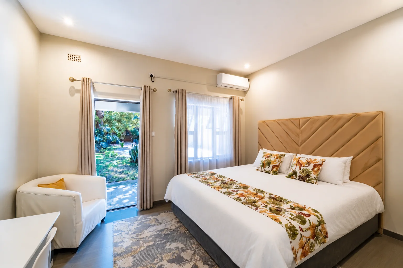 Guest Double Bedroom 1 with warm golden headboard and a door to the garden