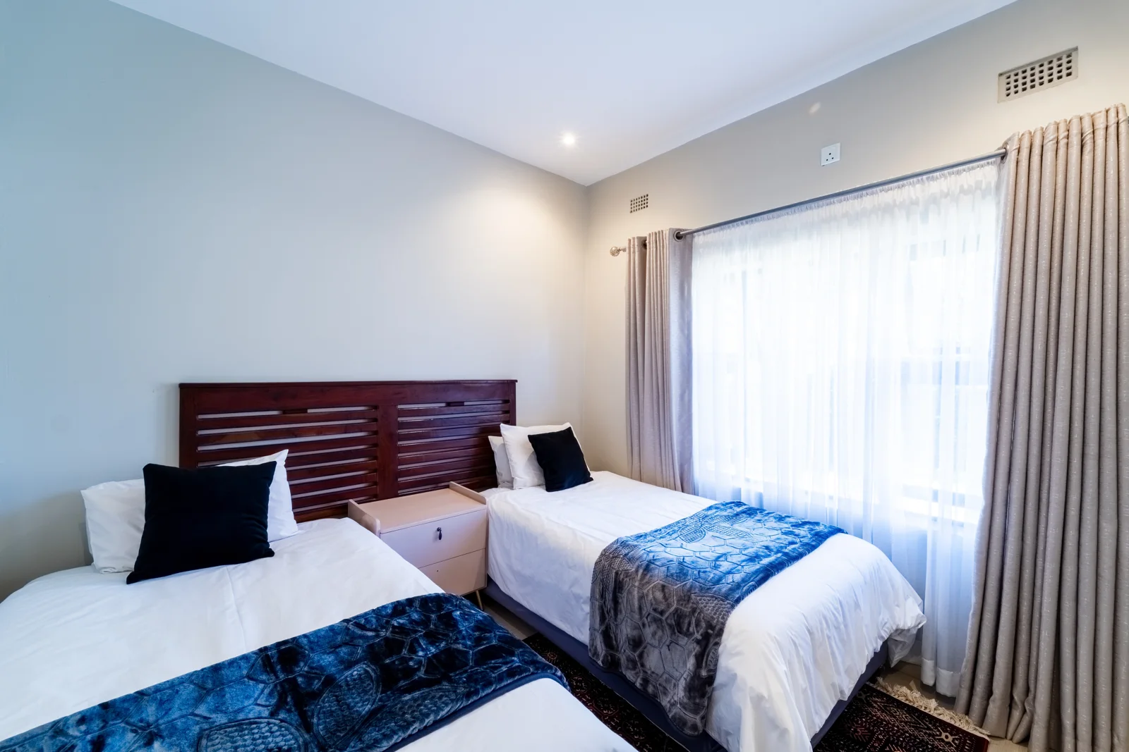 Twin Room 2 with two single beds, blue accents and a garden view